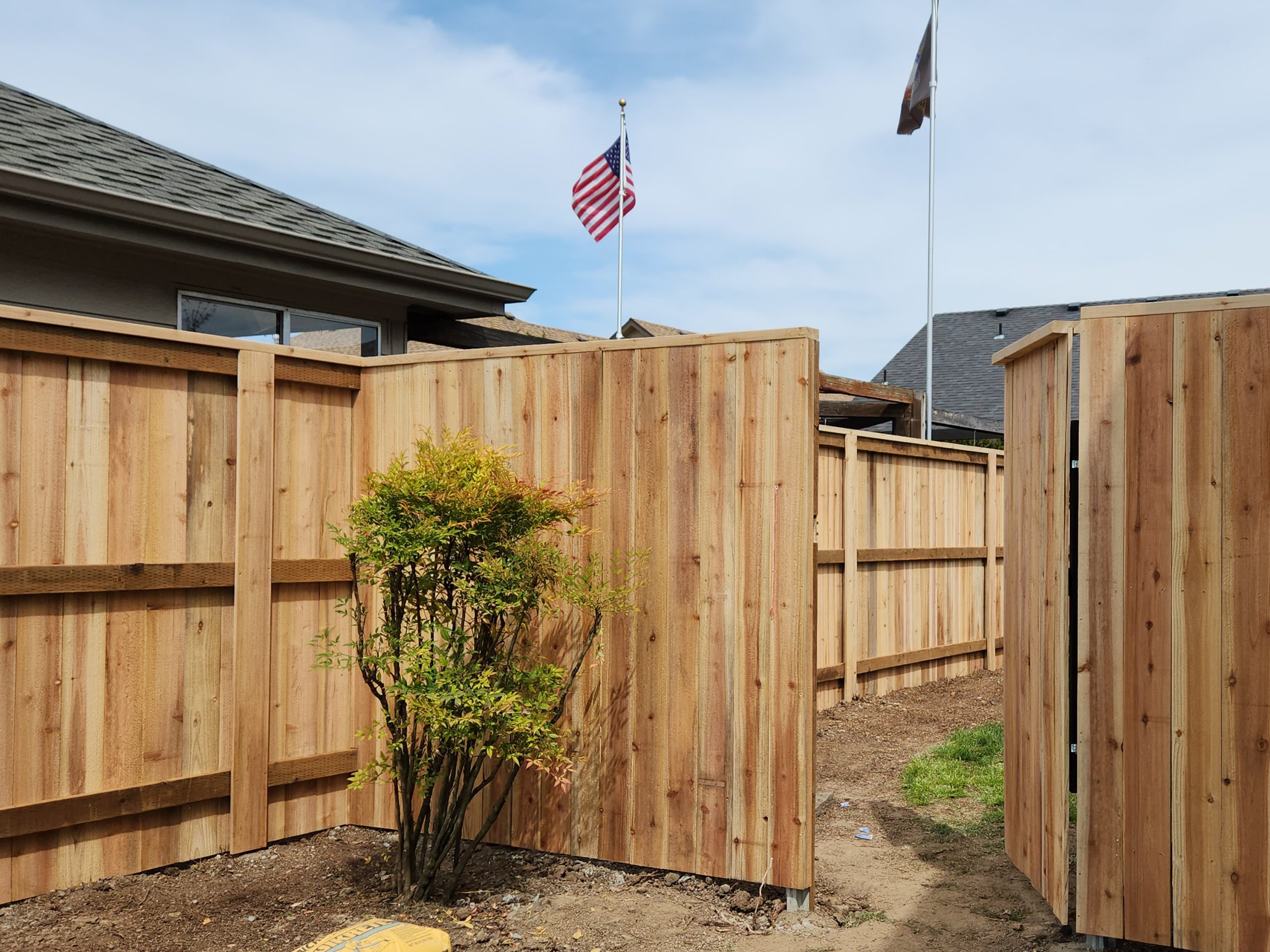 Wooden fence by Casa Bella Construction with a gate into the backyard.